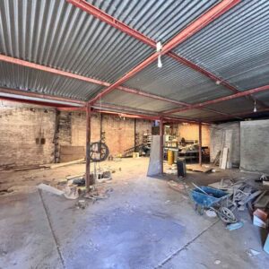 Interior del galpón con estructura metálica y muros de ladrillo, ideal para taller o corralón