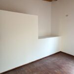 Pared con nicho, piso de madera y techo con vigas de madera en planta alta.